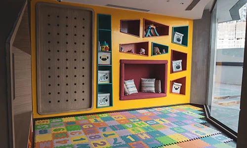 A children's room in an Aeon Luxe condominium with a colorful floor and bookshelves.