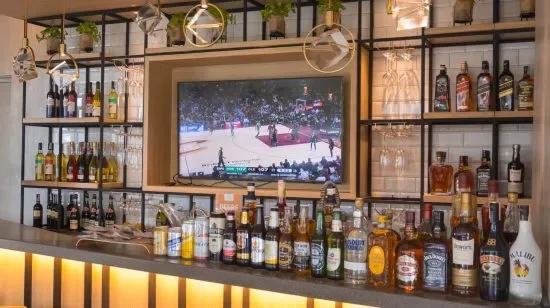 A club aeon bar with many bottles and a tv.